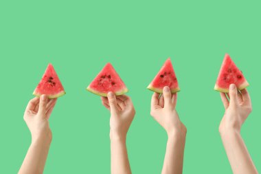 Yeşil arka planda olgun karpuz dilimleriyle kadın elleri.