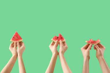 Yeşil arka planda olgun karpuz dilimleriyle kadın elleri.