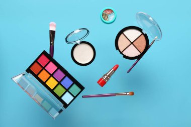 Mavi arka planda uçan dekoratif kozmetik ürünleri