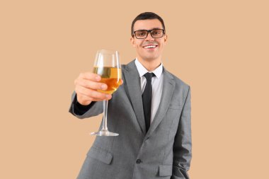 Bej arka planda bir bardak şarabı olan genç bir iş adamı.