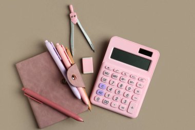 Kalem, pusula, hesap makinesi, not defteri ve silgiyle bej arka planda kompozisyon. Üst görünüm