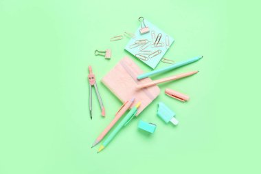 Yeşil arka planda not defteri ve farklı okul sayfası olan kalemler