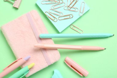 Farklı okul kağıtları ve yeşil arka planda not defteri olan kalemler.