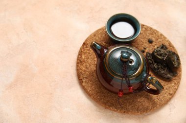 Çaydanlıklı mat, bej arka planda seramik fincan aromatik puer çayı.