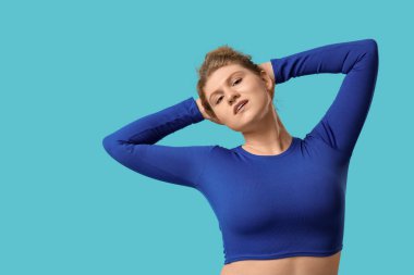 Mavi arka planda gerinen genç bir kadın.