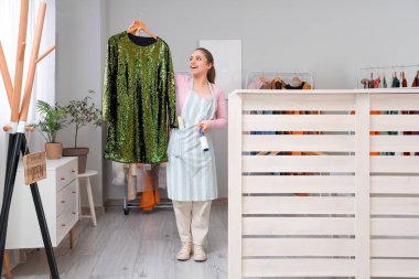 Tiftik silindirli ve kuru temizlemecide giyinen genç bir bayan işçi.