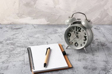 Çalar saat, defter ve kalem içeren kompozisyon grunge arkaplanına karşı. Zaman yönetimi