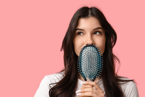 Красивая молодая женщина с расчёской на розовом фоне