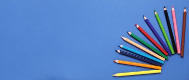 Mavi arkaplanda renkli kalemler ve metin için boşluk