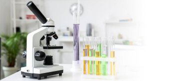 Laboratuvardaki masada mikroskop ve test tüpleri var. Tasarım için pankart