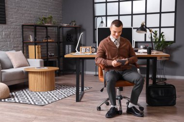 Ofiste oturan tabletli yakışıklı genç iş adamı.