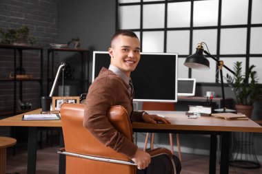 İş yerinde oturan yakışıklı genç iş adamı.