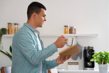 Yakışıklı genç adam mutfakta kitap okurken kahve içiyor.