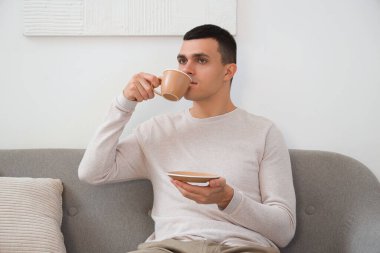 Evde kanepede otururken içme kahve yakışıklı genç adam
