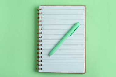 Yeşil arkaplanda defter olan kalem