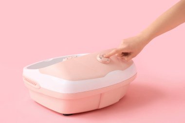 Pembe arka planda ayak banyosu yapan bir kadın el.