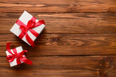 Tahta arka planda kırmızı kurdeleyle bağlanmış hediye kutuları. Üst görünüm