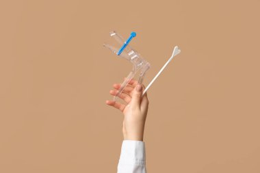 Bej arkaplan üzerinde pap test araçları ile doktor eli