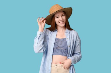 Mavi arka planda şapkalı şık genç kız.