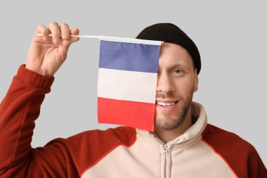 Açık arkaplanda Fransa bayrağı taşıyan genç bir adam
