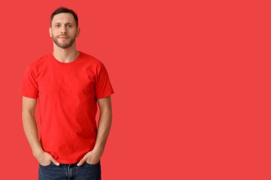 Kırmızı arka planda şık tişörtlü adam.