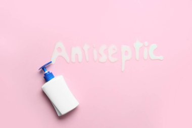 Kelime ANTISEPTIC pembe arka planda bir şişe dezenfektan ile yapıldı