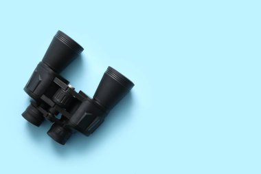 Black binoculars on blue background