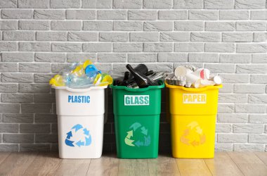 Gri tuğla duvarın yanında farklı çöp kutularıyla dolu. Geri dönüşüm kavramı