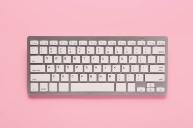 Pembe arka planda gri bilgisayar klavyesi. Üst görünüm