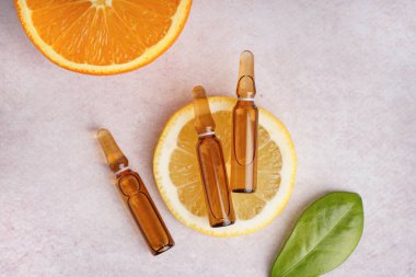 C vitamini ve hafif arkaplanda taze narenciye içeren ampuller.