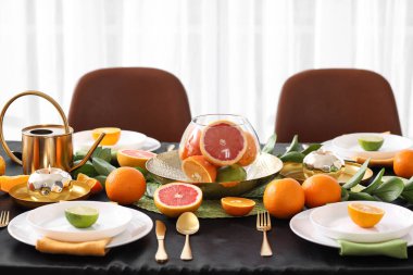 Oturma odasında turunçgil meyveleri, yanan mumlar ve siyah masa örtüsü olan güzel bir masa.