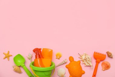Pembe arka plandaki çocuklar için güneş kremi ve plaj aksesuarlarıyla güzel bir kompozisyon