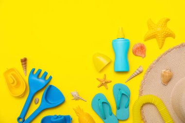 Sarı arka plandaki çocuklar için güneş kremi ve plaj aksesuarlarıyla güzel bir kompozisyon