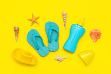 Sarı arka plandaki çocuklar için güneş kremi ve plaj aksesuarlarıyla güzel bir kompozisyon