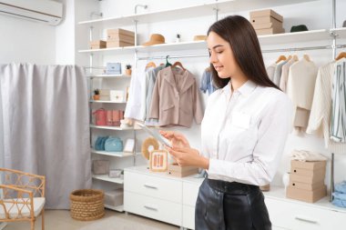 Tablet bilgisayarlı kadın satıcı giyim mağazasından online sipariş alıyor