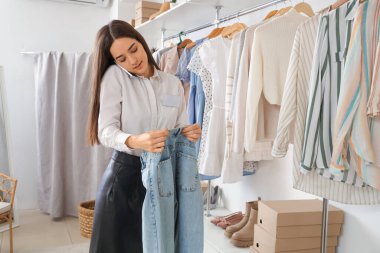 Kotlu kadın satıcı giyim mağazasında cep telefonundan online sipariş alıyor.