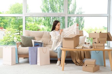 Evde internetten sipariş edilmiş kıyafetleri olan genç bir kadın.