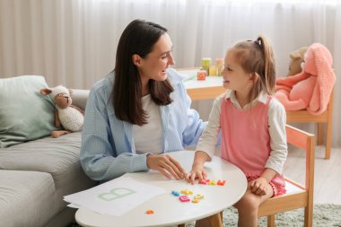 Ofiste küçük bir kızla çalışan kadın konuşma terapisti.