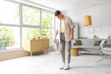 Genç adam ağırlığını evde tartıyla ölçüyor.