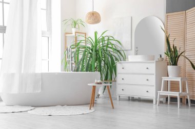 Banyonun içinde küvet, perde ve palmiye ağaçları var.