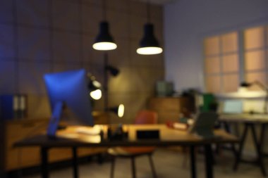 Masaları ve parlak lambaları olan karanlık ofisin bulanık görüntüsü