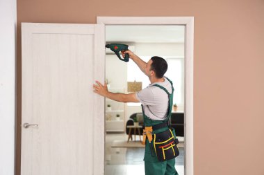 Evde elektrikli matkapla çalışan erkek işçi.