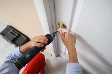 Elektrikli matkapla çalışan erkek işçi. Evinin kapısını onarıyor. Kapalı.