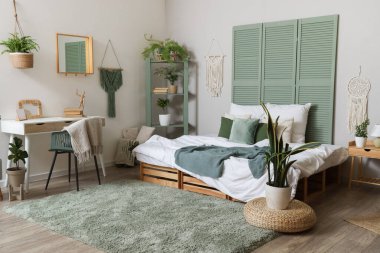 Şık bir yatak odası, rahat bir yatak odası, çalışma alanı ve çiçekleri var.