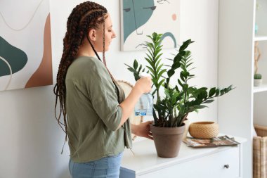 Evinde rastalı sulama bitkisi olan genç bir kadın