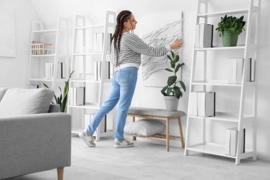 Evinde duvarına 3 boyutlu resim asan rastalı genç bir kadın.