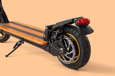 Kahverengi arka planda modern elektrikli scooter, yakın plan.