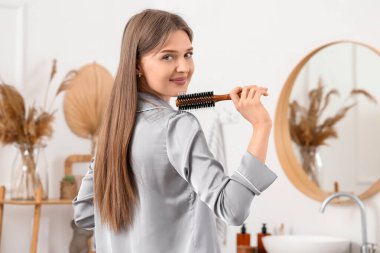 Banyoda saç fırçası olan genç bir kadın.