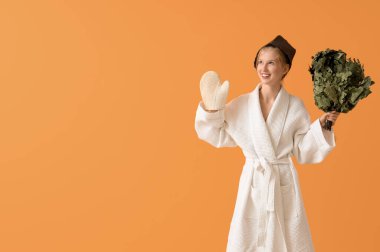 Sauna şapkalı, masaj eldivenli ve turuncu arka planda genç bir kadın.