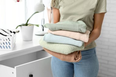 Güzel genç Afro-Amerikalı kadın, temiz giysileri evdeki klozete koyuyor, yakın plan.